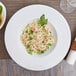 An Arcoroc white porcelain pasta bowl filled with shrimp and vegetable pasta.