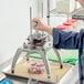 A person using a Nemco Easy Chopper III to dice vegetables into a plastic container.