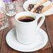 A Tuxton Bright White saucer with a cup of coffee on it.
