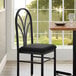 A black chair with a black fabric cushion next to a table.