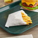 A tray with french fries and a cheeseburger in Carnival King medium french fry bags.