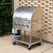 A stainless steel Backyard Pro roll dome lid on a grill with knobs and handles.