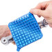 A hand holding a blue square Nemco push block cleaning gasket.