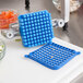 A blue square shaped machine with a blue Push Block Cleaning Gasket on a white cutting board.