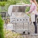 A woman cooking food on a Backyard Pro stainless steel outdoor grill on a table.