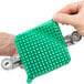 A hand holding a Nemco green plastic square with two silver screws.