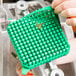 A person holding a green square Nemco push block.