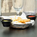 A black Tablecraft basket with chicken nuggets and fries with ramekins.