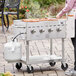 A woman cooking food on a Backyard Pro outdoor grill on a table.