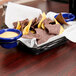 A Tablecraft black metal basket with ramekin holders filled with chips and dips on a table.