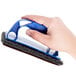 A hand holding a blue and black sponge from a grill and griddle cleaning kit.