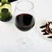 A Reserve by Libbey wine glass filled with red wine next to a plate of chocolate cake.