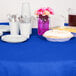 A royal blue Creative Converting OctyRound table cover on a table with plates and utensils.