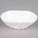 A bright white porcelain small elliptical bowl with a small design on it.