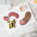 A stack of salami slices on a white slate rectangular porcelain platter.