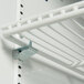 A white shelf with a metal clip on a white wall.