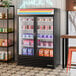 A black glass door merchandiser freezer with LED lighting, stocked with various frozen products.