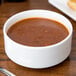 A 10 Strawberry Street white bone china bouillon bowl filled with red soup on a table.