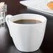 A white 10 Strawberry Street porcelain cappuccino cup filled with coffee on a table.