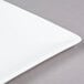 A close-up of a 10 Strawberry Street white square bone china plate with a white rim.