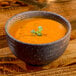 A 10 Strawberry Street Whittier stoneware bowl of orange soup with a small green leaf.