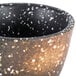 A white stoneware sake cup with black and brown speckles.