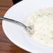 A 10 Strawberry Street white bone china bowl of soup with a spoon.