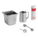 A silver Urnex Cafiza powder container with a black handle on a counter with metal measuring cups.