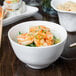 A bowl of shrimp and rice on a table with chopsticks.