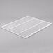 A white coated wire shelf on a gray surface.