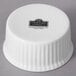 A white porcelain fluted ramekin with a logo on it.