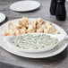 A white porcelain oval dish with food on a table.