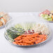 A Durable Packaging clear plastic high dome lid on a tray of baby carrots in a plastic container.