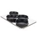 A metal tray with four black pans.