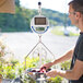 A man weighing a bowl of fruit on a Cardinal Detecto portable scale stand.