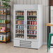 A white two-section glass door merchandiser refrigerator filled with various beverages.