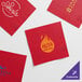 A group of red Choice 2-ply customizable beverage napkins with white and gold logos.