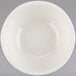 A white Tuxton China bowl with a white rim on a gray surface.