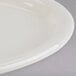 A white Tuxton oval china platter with a narrow rim on a gray surface.