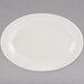 A white Tuxton oval china platter with a wide rim on a gray surface.