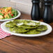 A Tuxton eggshell china platter with green ravioli and salad on it.