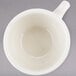 A close-up of a Tuxton Nevada eggshell china cup with a handle.