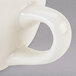 A close up of a white Tuxton Nevada china cup with a handle.