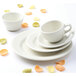 A close up of a Tuxton Nevada eggshell white cup on a saucer.