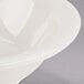 A Tuxton Nevada narrow rim china fruit bowl on a gray surface.