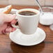 A hand holding a Tuxton Nevada saucer with a cup of coffee.