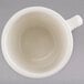 A white Tuxton tall china cup with a handle.