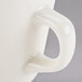 A white Tuxton tall china cup with a handle.