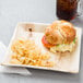 A croissant sandwich and chips on an EcoChoice palm leaf plate with a drink.