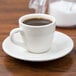 A Tuxton Reno espresso saucer with a cup of coffee on it.